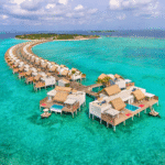 Aerial view of overwater villas stretching in a curve over turquoise waters at the Emerald Maldives Resort & Spa.