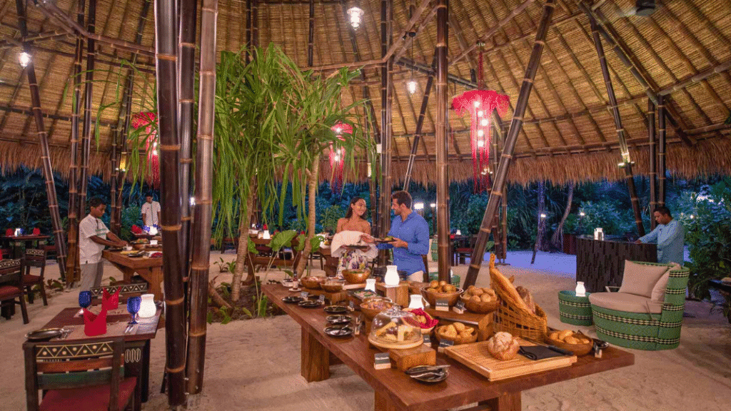 Guests enjoy an evening buffet in a stylish open-air restaurant with bamboo architecture at Emerald Maldives Resort & Spa.