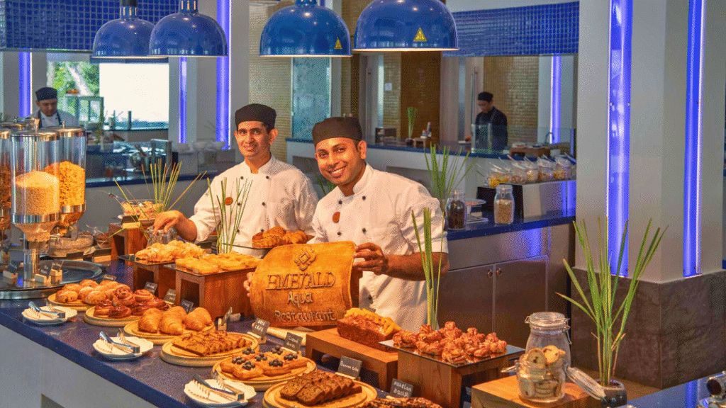 Two chefs present a breakfast pastry buffet at Emerald Aqua Restaurant, featuring a wide selection of fresh baked goods and cereals.