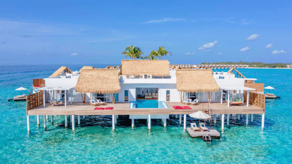 A luxurious overwater villa at Emerald Maldives Resort And Spa, featuring thatched roofs, a private pool, and direct access to the turquoise lagoon.