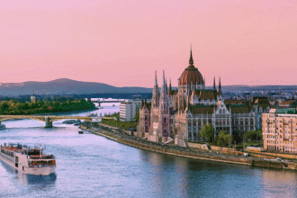 River cruise ship passing Budapest’s Parliament building at sunset, capturing the elegance and cultural highlights of river cruising in Europe.
